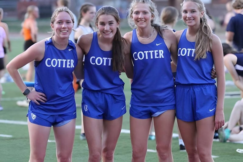 Un grupo de jóvenes atletas de las Cotter Schools está de pie juntos en el campo deportivo.