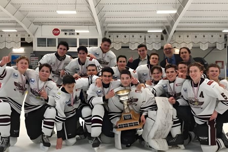 Un grupo de estudiantes de la Cowichan Secondary School posan en la sala de hockey junto a un trofeo.