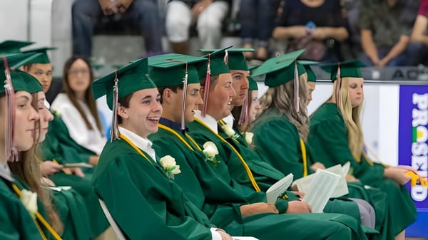 Un grupo de graduados de la Craigslea State High School lleva togas verdes y está sentado junto en la ceremonia de graduación.