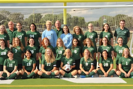 Un grupo de jóvenes futbolistas posa en el campo de juego del Cranbrook Education Campus frente a la portería.