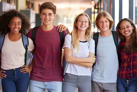 Un grupo de estudiantes se encuentra juntos y sonríe en el terreno de la Crescent Heights High School.