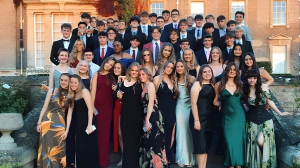 Un grupo de estudiantes de la Culford School está en ropa formal frente a un edificio histórico en el campus.