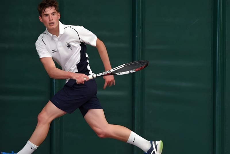 Un joven tenista se prepara en la cancha de tenis de la Culford School para un golpe.