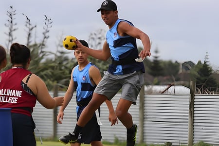 Un grupo de estudiantes juega al fútbol en el campo deportivo del Cullinane College frente a una cerca de metal.