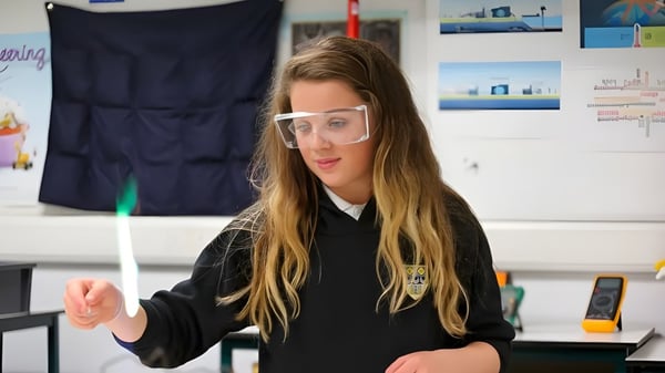 Una estudiante de la Currie Community High School lleva unas gafas de protección y está en un aula con carteles educativos.