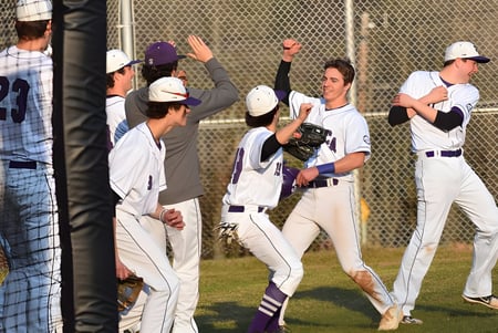 Estudiantes de la Cushing Academy celebran juntos en el campo de béisbol frente a los espectadores detrás de la valla.