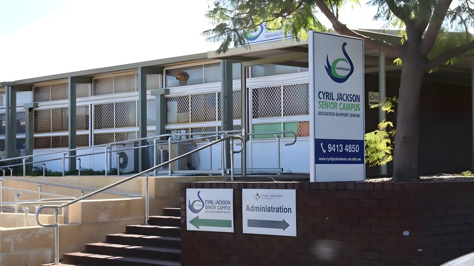 El edificio de varios pisos del Cyril Jackson Senior Campus muestra el logo verde y la entrada con escalones y árboles.