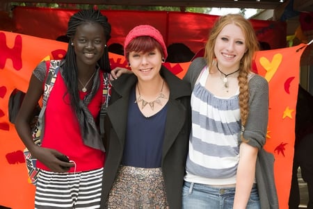 Tres jóvenes estudiantes están frente a un colorido motivo de corazón en el Cyril Jackson Senior Campus.