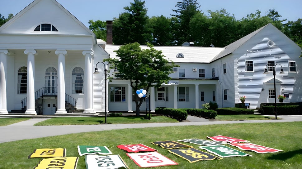 El césped bien cuidado y los coloridos letreros frente al edificio de estilo colonial en el campus de la Dana Hall School.