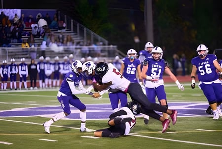Partido de fútbol con jugadores en tacleo en el campo de la Darlington School frente a espectadores.