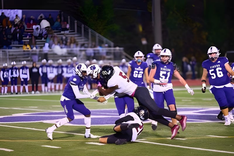 Partido de fútbol con jugadores en tacleo en el campo de la Darlington School frente a espectadores.