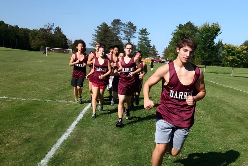 Un grupo de estudiantes de la Darrow School camina por un campo deportivo con árboles al fondo.