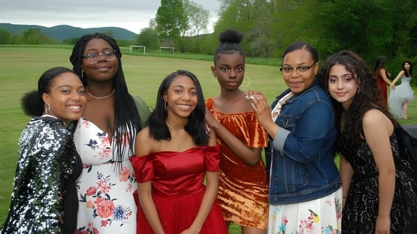 Un grupo de estudiantes de la Darrow School está en el área exterior verde con montañas al fondo.