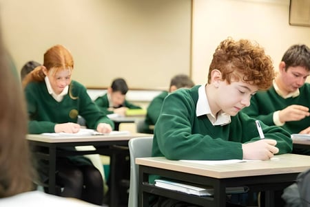 Estudiantes del Davitt College están sentados en un aula y se concentran en su trabajo.