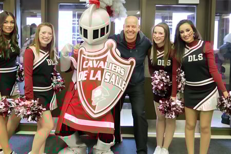 Las animadoras y la mascota posan juntas en rojo y negro en el campus de la École secondaire publique De La Salle.
