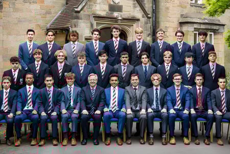 Un grupo de estudiantes en uniforme está frente al edificio histórico de piedra con torre en el terreno del De la Salle College (Macroom).