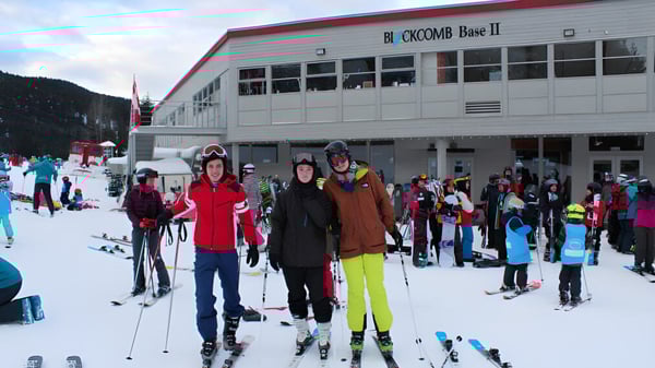 Un grupo de alumnas y alumnos de la Delta Secondary School está vestido de invierno frente a una cabaña de esquí en una pista nevada.