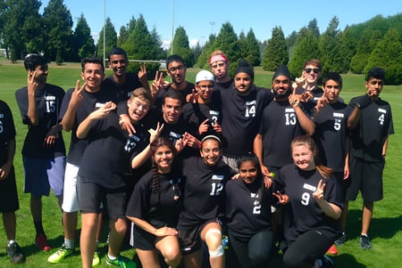 Un grupo de estudiantes de la Delview Secondary School posa juntos en un campo de césped con árboles de fondo.