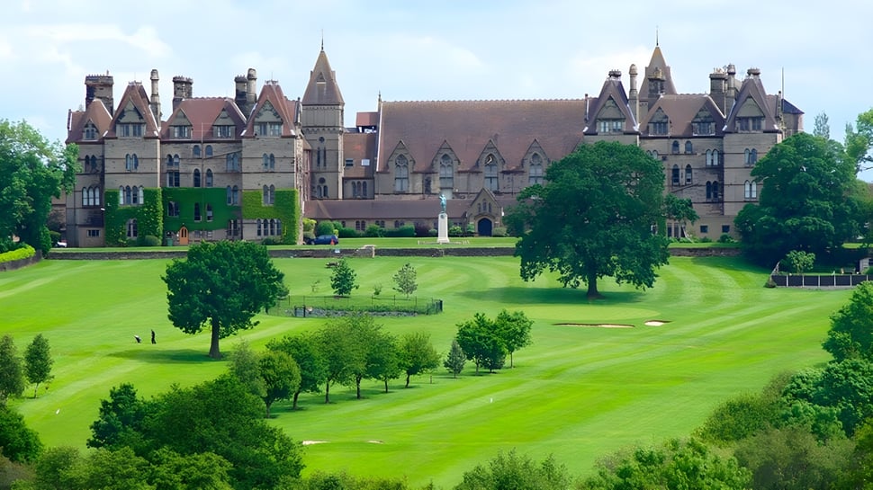 El castillo medieval en el terreno del Denstone College se encuentra en un cuidado césped verde con árboles.