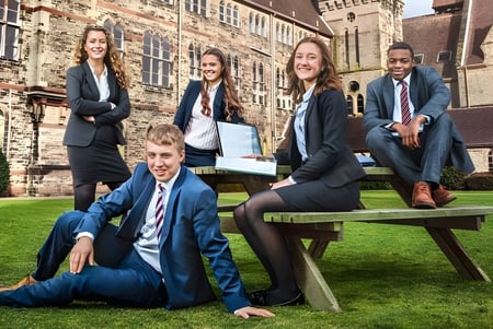Un grupo de estudiantes del Denstone College posan en un área de césped frente a un edificio histórico.