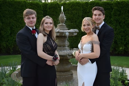 Cuatro personas posan frente a una fuente en el terreno de la Devonport High School.
