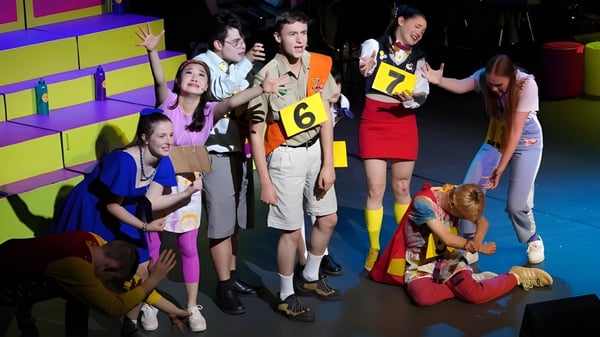 Un grupo de estudiantes del Dickson College se reúne en la parte trasera del escenario con un colorido telón de fondo.