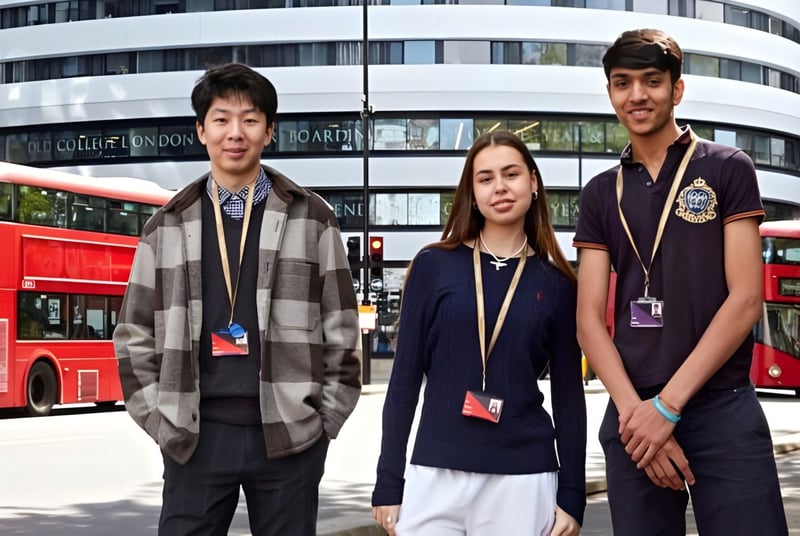 Tres estudiantes están frente a un edificio moderno en el campus del DLD College London con autobuses de dos pisos rojos de fondo.