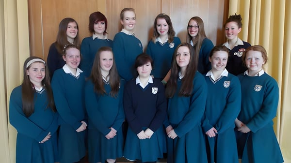 Un grupo de alumnas en uniforme escolar uniforme está frente a una pared revestida de madera en el campus del Dominican College Wicklow.