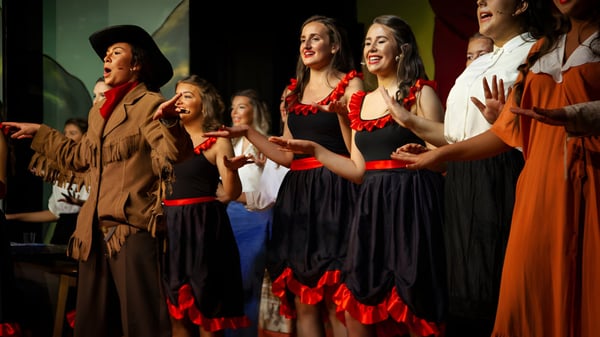 Un grupo de alumnas del Dominican College Galway actúa en vestidos tradicionales en un escenario.