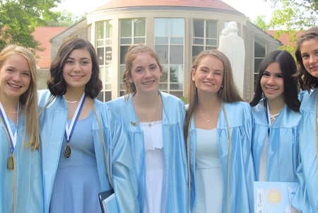 Un grupo de graduadas en togas azules está frente a un edificio con cúpula en el campus del Dominican College Wicklow.