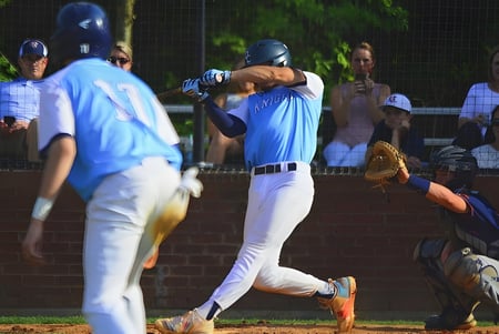 Estudiantes de la Dominion Christian School juegan un partido de béisbol en el campus escolar frente a espectadores.