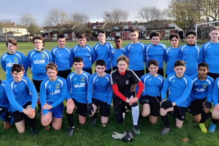 Un grupo de jóvenes futbolistas de la Donahies Community School posan en el campo para una foto de equipo.