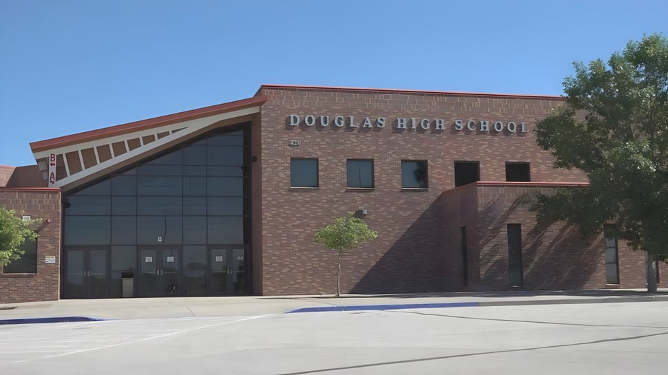 El edificio de ladrillo de la Douglas Community School está rodeado de árboles y un patio pavimentado.