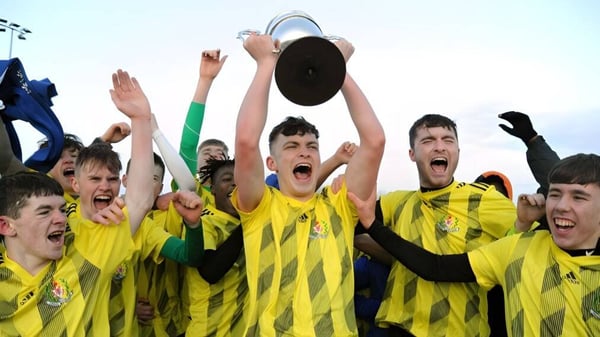 Un grupo de jóvenes futbolistas celebra con un trofeo en el campo de la Douglas Community School.