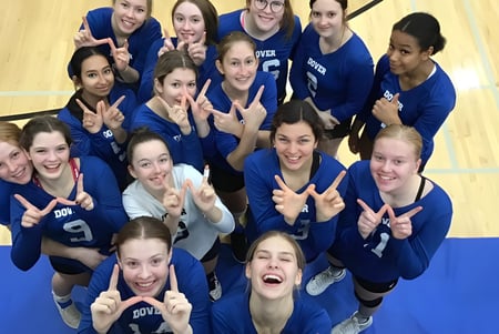 Un grupo de alumnas de Dover Bay Secondary School muestra signos de paz en el gimnasio y ríen juntas.