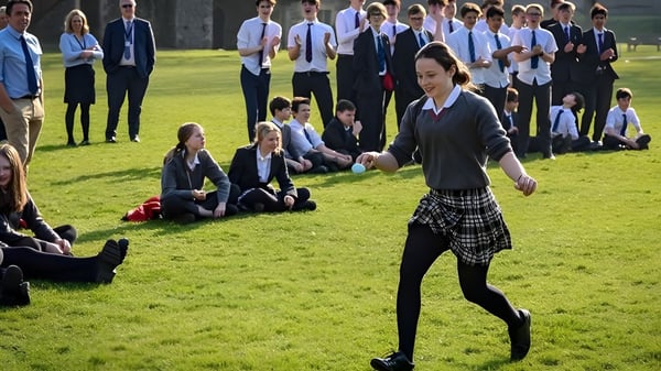 Estudiantes del Dover College realizan un ejercicio de danza y movimiento en grupo en un campo.
