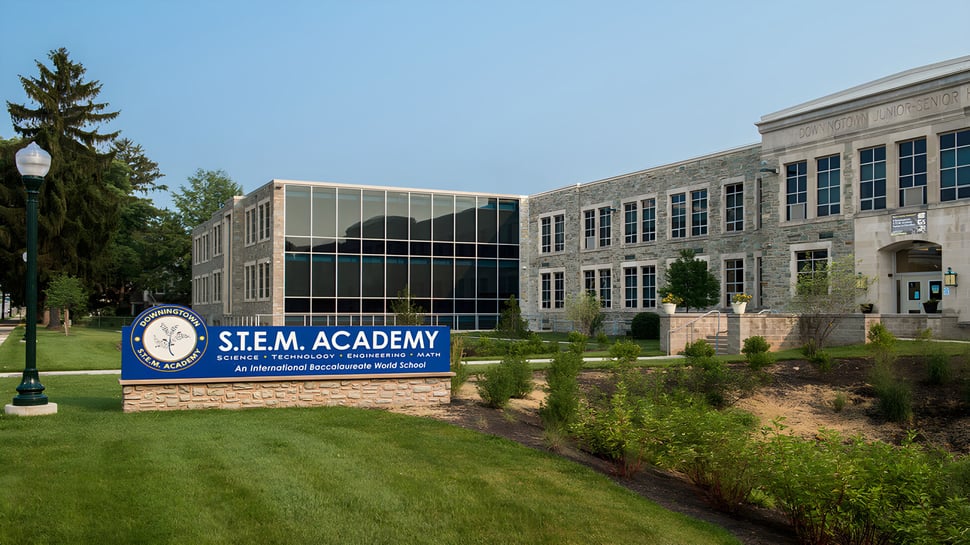 El edificio de ladrillo de varios pisos del Downingtown Area School District se encuentra en un terreno cuidado con árboles.