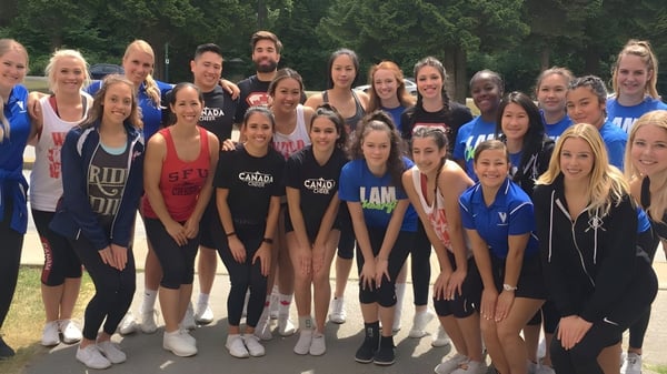 Un grupo de estudiantes de la Dr. Charles Best Secondary School está juntos afuera en un área parecida a un parque con árboles de fondo.