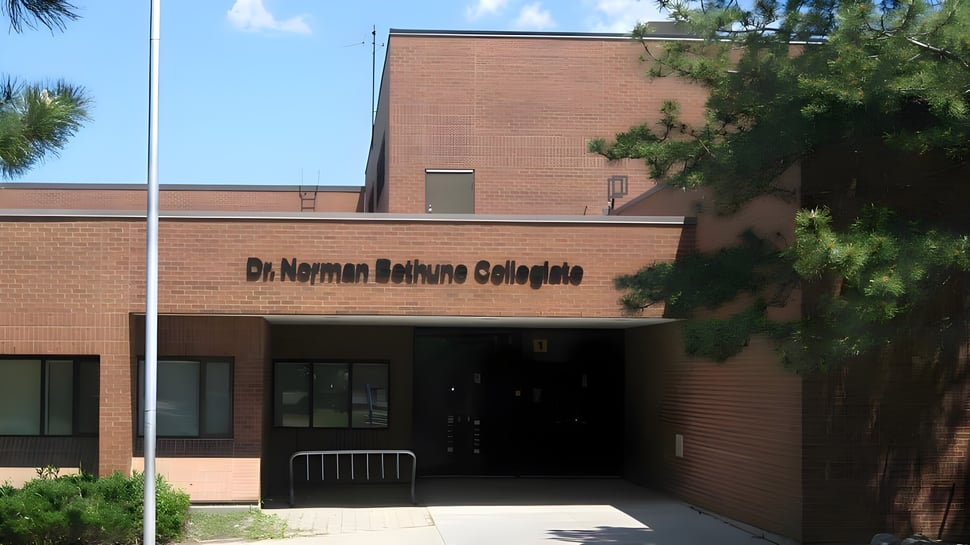 El edificio de ladrillo del Dr. Norman Bethune Collegiate Institute con árboles circundantes y cielo despejado.