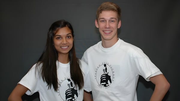 Dos estudiantes de la Dunbarton High School están frente a un fondo oscuro y sonríen a la cámara.