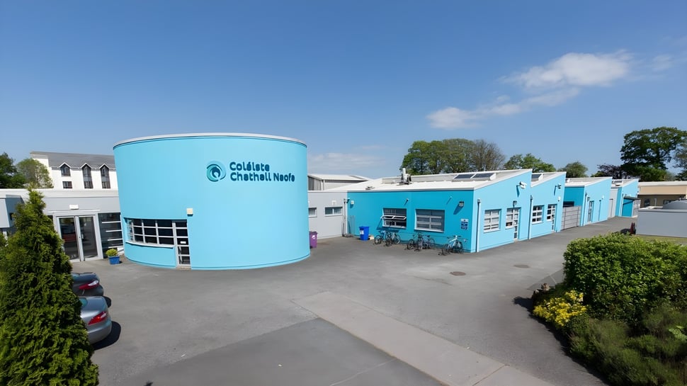 El moderno y colorido edificio del Dungarvan College con una gran estructura cilíndrica bajo un cielo azul.