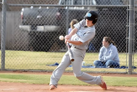Un jugador de béisbol de Eagle Butte High School está en el montículo frente a una cerca con espectadores al fondo.