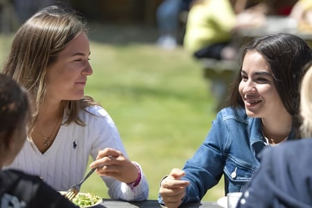Dos alumnas conversan en el área exterior de la Earlscliffe School en un campo.