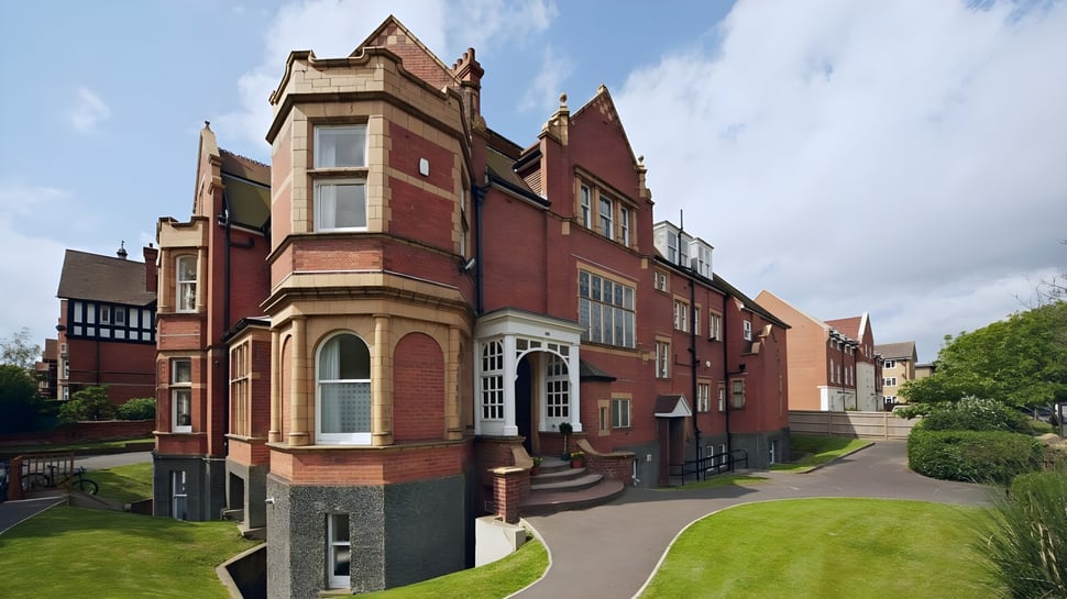 El histórico edificio de ladrillo en el campus de Earlscliffe está rodeado de césped bien cuidado y vegetación verde.