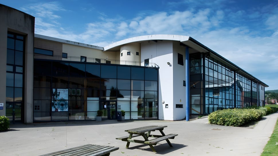 El moderno edificio con fachada de vidrio y techo curvado en el campus del East Sussex College Eastbourne.