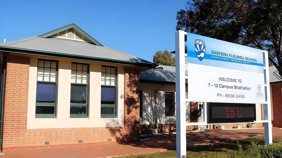 El edificio de ladrillo con techo verde en el terreno de la Eastern Fleurieu R-12 está rodeado de árboles.
