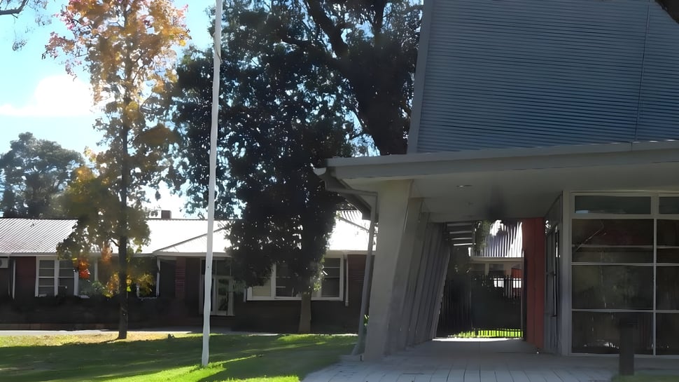 El edificio residencial con entrada cubierta se encuentra en el terreno de la Eastern Hills Senior High School y está rodeado de árboles.