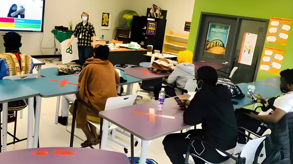 Estudiantes de la École secondaire publique L'Alternative están activos en un aula colorida con materiales de aprendizaje.