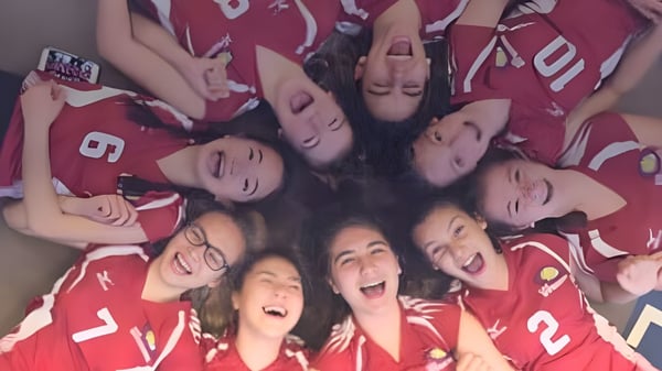 Un grupo de jóvenes alumnas en camisetas rojas se reúne en el campus de École Arc-en-ciel.