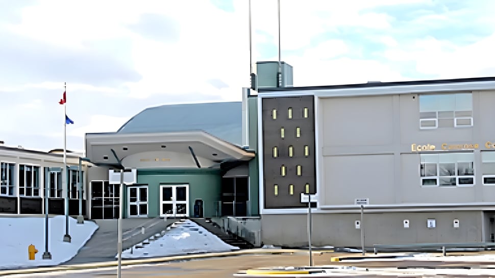 El moderno edificio de la École Camrose Composite High School con arquitectura llamativa y un patio pavimentado bajo un cielo nublado.